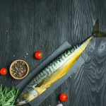 Cold smoked mackerel on a cutting board. Sea products. Dark wooden background.